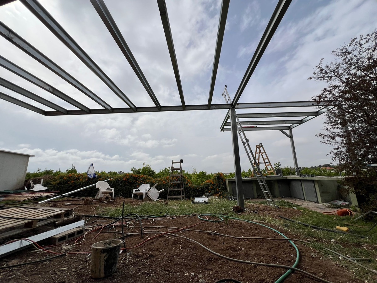 פרגולת ברזל בהתקנה בחצר פרטית